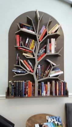 there is a book shelf with many books on it and a tree in the middle