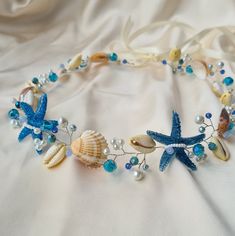 a necklace with starfishs, seashells and pearls on white satin background