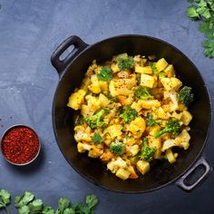 a pan filled with vegetables and spices next to some parsley on a table top