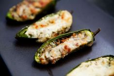 several green peppers with cheese on them sitting on a black surface