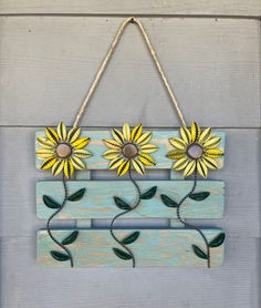 a wooden sign with sunflowers hanging from it