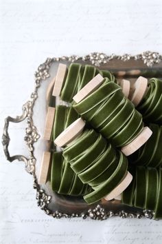 some green and white cookies on a silver platter with writing in the back ground