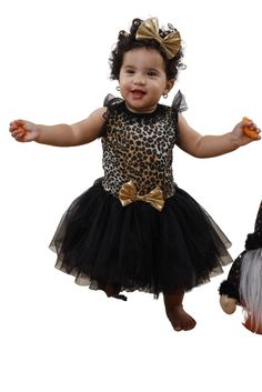 a baby girl wearing a leopard print dress and black tutu skirt with gold bows