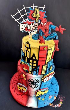 a three tiered cake decorated with spiderman and batman symbols on it's sides