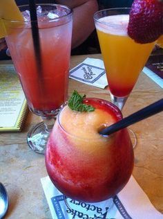 three different types of drinks sitting on a table next to each other with strawberries