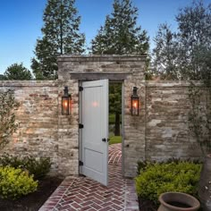 an entrance to a home with brick walls and doors leading into the yard at dusk