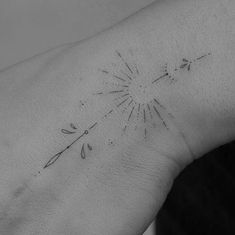 a black and white photo of a person's wrist with a dandelion tattoo