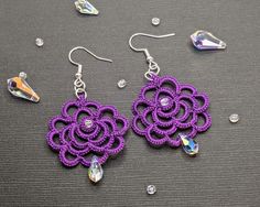 purple crochet flower earrings with swarong crystals on grey surface next to crystal beads