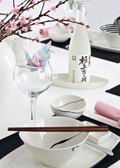 a white table topped with plates and bowls filled with food next to a vase full of flowers