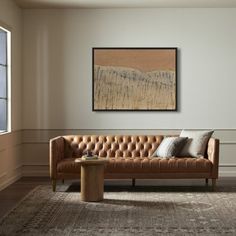 a living room with a couch, coffee table and large painting hanging on the wall