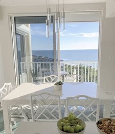 a bowl of grapes and nuts sits on a table in front of a window overlooking the ocean