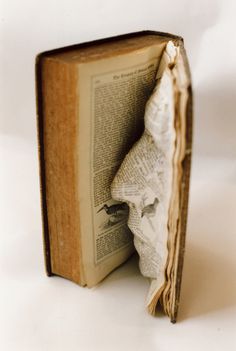 an open book sitting on top of a white table next to three small balls of dirt