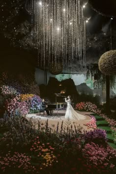 a bride and groom standing in front of a piano surrounded by flowers with chandeliers hanging from the ceiling