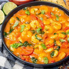 a pan filled with shrimp and vegetables on top of a blue towel next to bread