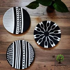 three black and white plates sitting on top of a wooden floor next to a potted plant