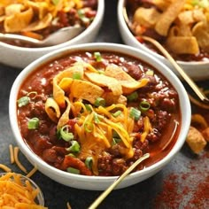 three bowls filled with chili, cheese and tortilla chips on top of a table