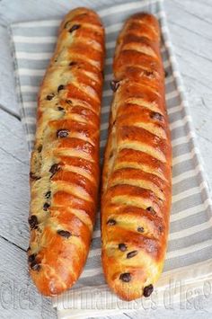 two long loafs of bread sitting on top of a white and gray striped towel