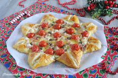 a star shaped pizza sitting on top of a white plate next to red and green decorations