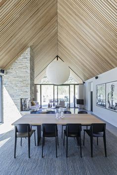 a dining room table and chairs in front of a large window with wooden ceilinging