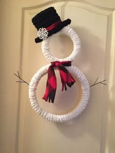 a snowman made out of yarn is hanging on a door handle with a red and black scarf around it