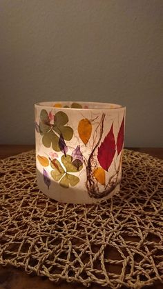 a white bowl with leaves on it sitting on top of a doily tablecloth