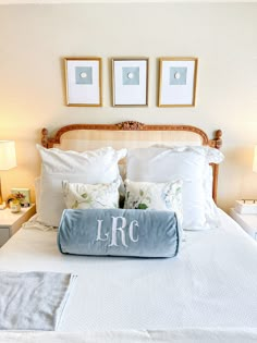 a bed with pillows and blankets on top of it next to two framed pictures above the headboard