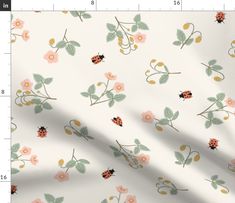 a white fabric with pink flowers and ladybugs on it, next to a ruler