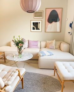 a living room filled with white furniture and lots of pictures on the wall above it