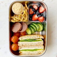 a bento box filled with fruit, veggies, and meat on top of it