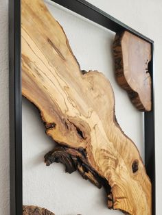 some wood pieces are hanging on the wall in front of a white wall and black frame