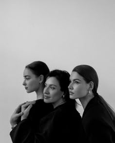 three women standing next to each other in black and white