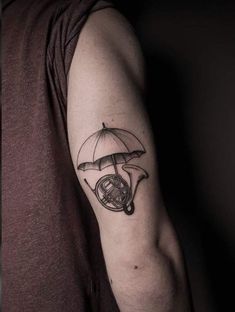 a man with a tattoo on his arm has an umbrella and french horn in it