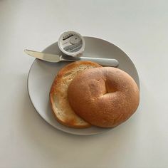 a white plate topped with a bagel next to a knife and butter on top of it