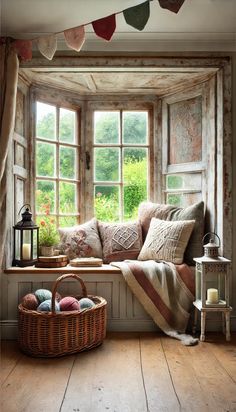 a window seat with pillows and blankets on it next to a basket filled with balls