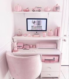 a desk with a computer on top of it and pink accessories in front of the monitor