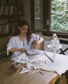 a woman sitting at a table working on crafts