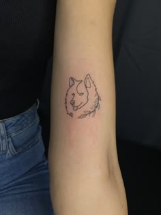 a woman's arm with a small tattoo of a dog on the left side