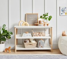 a white shelf with some toys on top of it and a potted plant next to it