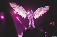 an angel statue is on display in front of a crowd at a music concert with purple lighting