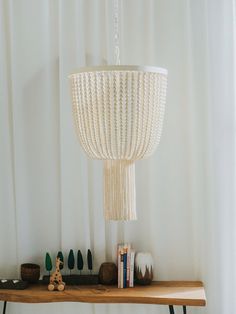 a wooden table topped with a white chandelier hanging from it's side