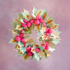 a christmas wreath made out of paper with red berries and green leaves on the top