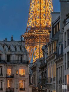 the eiffel tower lit up at night in paris, france with buildings around it