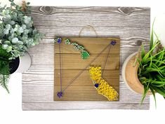 a piece of wood with beads and plants on it next to a potted plant