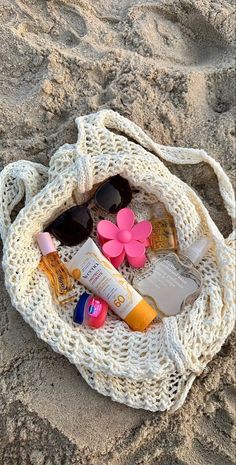 a white bag filled with lots of items on top of a sandy beach