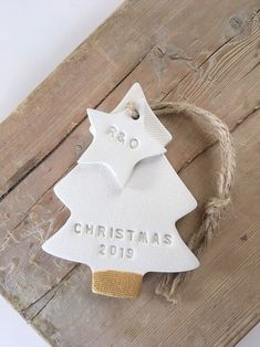 a white ceramic christmas tree ornament hanging from a rope on a wooden board