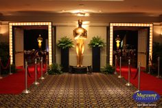 an oscar statue is in the middle of a red carpeted area with barriers and lights