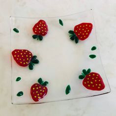 some red strawberries on a glass plate with green leaves and dots in the middle