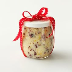 a jar filled with food sitting on top of a white table next to a red ribbon