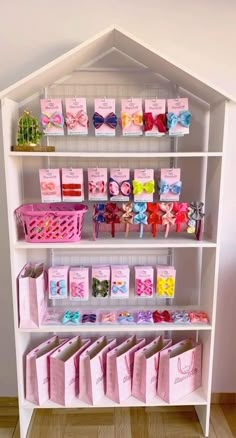 a white shelf filled with lots of pink and purple bags on top of each shelf