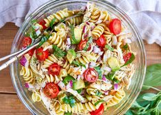 a glass bowl filled with pasta salad on top of a wooden table